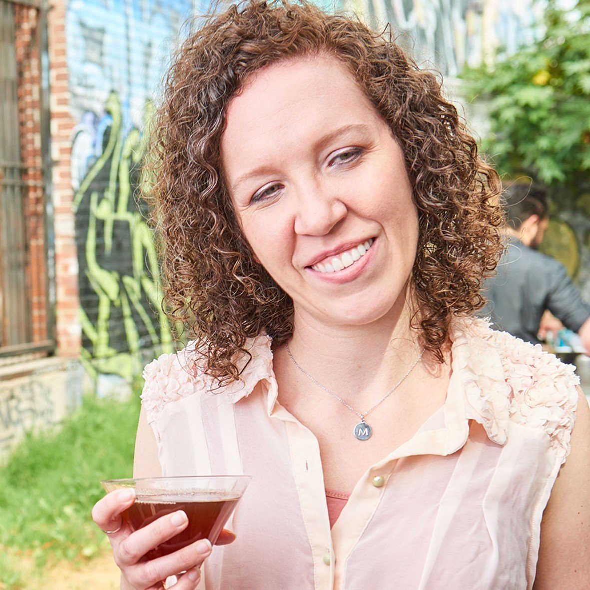 Woman holding red cocktail with Greenbar Hibiscus liqueur